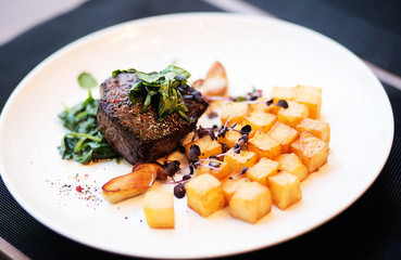 beef  Steak with roasted potato wedges on white plate