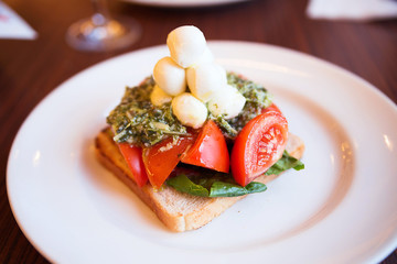 appetizer of mozzarella, toast, pesto and tomato