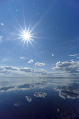 River view with clouds reflected in it, the sun in the frame, Volga, Russia