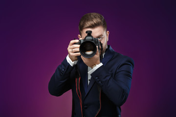 successful professional photographer in tuxedo use DSLR digital camera on dark background