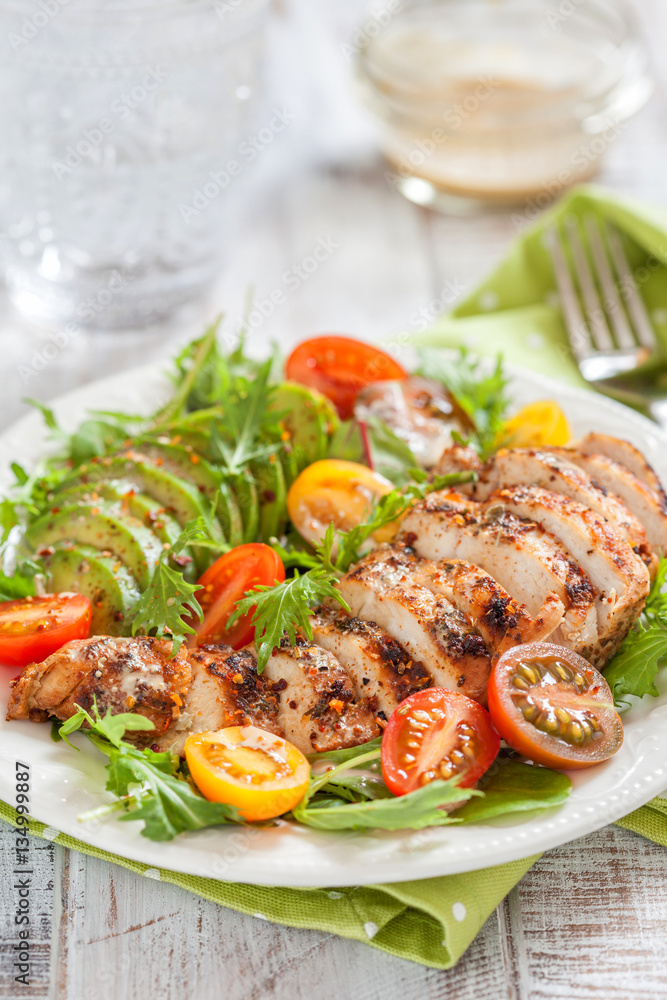 Wall mural healthy salad plate with colorful tomatoes, chicken breast and avocado