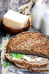 Sliced  homemade rye bread on baking paper and bottles of milk o