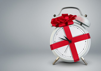 Clock in gift ribbon on grey, time to gift cocept, copy space.