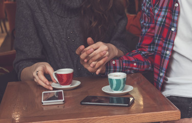 Loving couple sitting together in cafe and holding hands