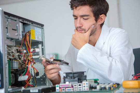 Confused computer technician studying component