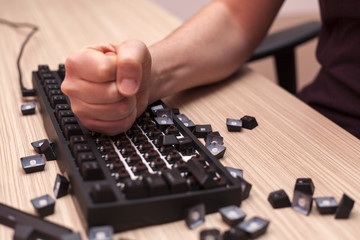 Man smashes a mechanical computer keyboard in rage using one fist - obrazy, fototapety, plakaty
