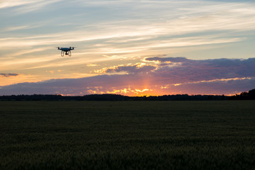 Naklejka na ściany i meble Drone silhouetted against orange sunset