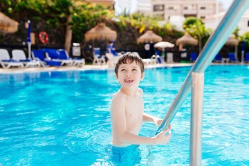 Happy child playing in hotel pool.