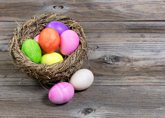 Close up front view of colorful Easter eggs in bird nest on wood