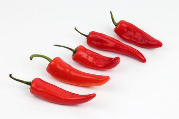 five bright red sweet peppers on a white background