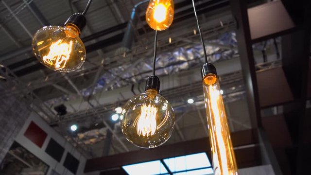 Four old-style light bulbs hanging on a wire on the background of the high ceiling of the hangar. Shot in motion