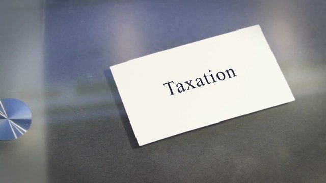 Hand puts business card on table with text Taxation