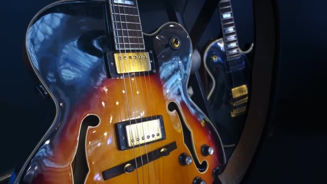 Beautiful varnished semi-acoustic guitar in retro style is on the stage in between performances of jazz group. Shot in motion
