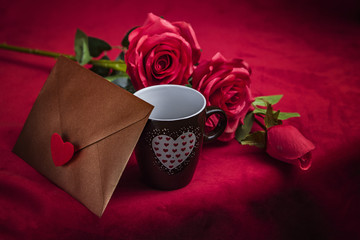 Obraz na płótnie Canvas Valentine's Day: Copper gold envelope, cup of coffee and red roses on dark red background