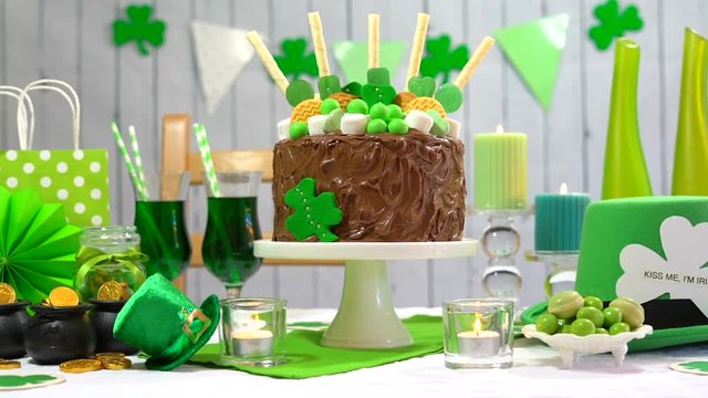 Happy St Patricks Day party table with chocolate cake decorated with cookies and candy, full table.