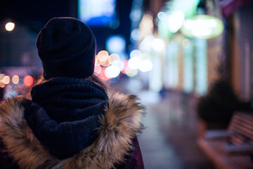 Hipster girl walking on city street at night