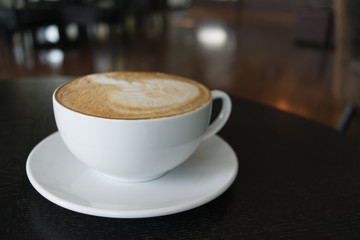 Cup of coffee on wooden table in cafe.