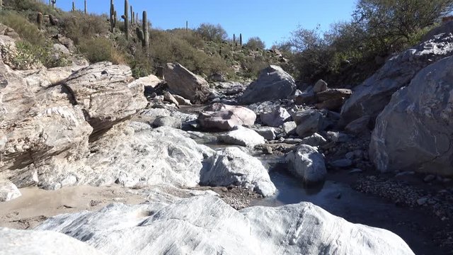 A daytime establishing shot of a small stream in the rocky Arizona desert. With audio.  	
