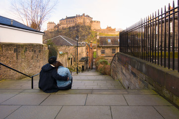 Pretty young couple sitting and looking at Edinburgh castle in E