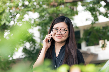 Asian glasses business women talking cellphone in park