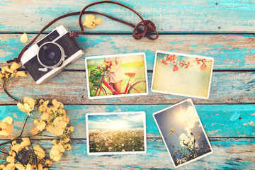 Retro camera and instant paper photo album on wood table with flowers border design - photo of...