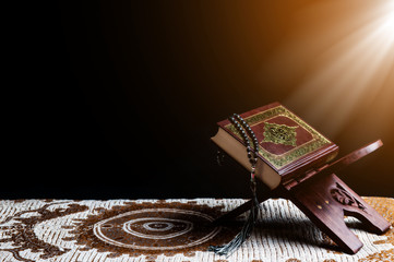 Islam holy book of Muslims, the Quran, is placed on a wooden stand, black background.