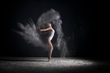 Fototapeta na wymiar Slender blonde dancing in white dust studio shot