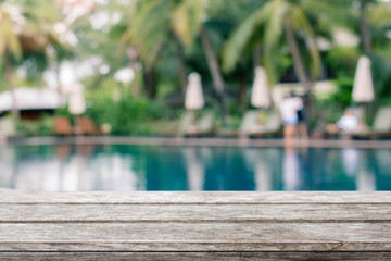 Wood table top and blurred swimming pool background.