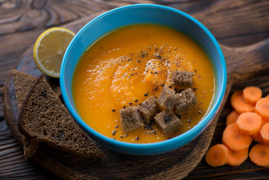 Carrot cream-soup with croutons served in a blue bowl, closeup