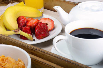 Breakfast tray with coffee, orange juice, cereals and fruits.