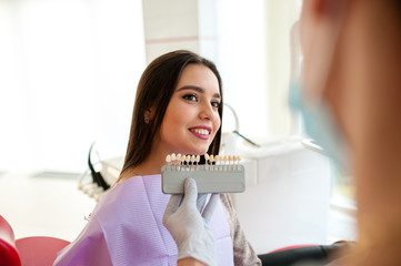 Selection color of teeth in dentistry girl