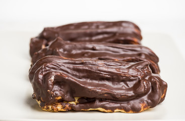 Chocolate eclair on the white table. Shallow depth of field.