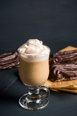 Coffee and chocolate eclair on dark wooden background. Shallow depth of field.