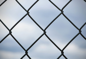 Barbed wire, fence in front of gray sky, background