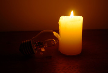 Burning candle and lamp on desktop.  Power outage.  Missing electricity - blackout begin.	