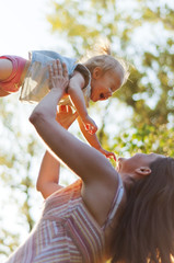 Naklejka premium Young mother throws his little daughter in the air