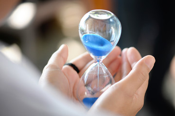 Hourglass that is located on the beautiful hands.