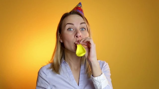 Girl inflating a balloon on a yellow background