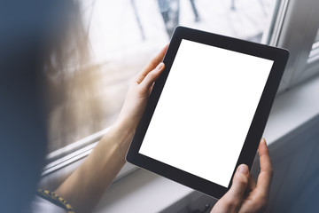 Hipster person hands holding digital tablet with empty blank screen, against a background of ...