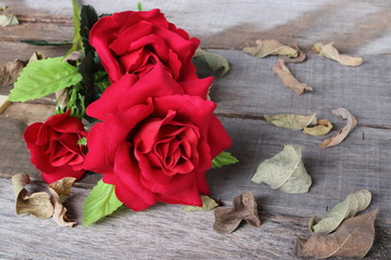 A beautiful artificial bouquet  of red roses on old wooden board with copy space background. Love and romance Valentine's day concept