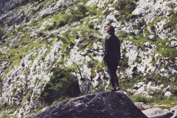 Obraz premium Happy tourist traveler standing on a rock, hiker looking to a valley below in trip in spain, hipster young girl enjoying peak of foggy mountain background green landscape view mockup