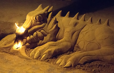 Sand dragon sculpture on the beach at night.