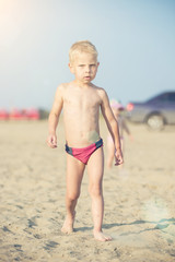 Baby boy walking on the sandy beach near the sea. Cute little kid at sand tropical beach. Ocean coast.