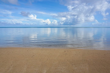Peaceful seascape horizon with beach sand in foreground and calm water surface of the lagoon of Huahine island, Pacific ocean, French Polynesia
