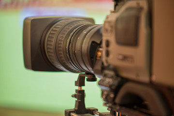 Fototapeta na wymiar The camera with a long lens. Recording TV program. On green background.
