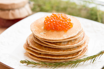 russian pancakes with red caviar on the white plate