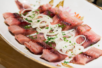 salty herring with white onion on the plate