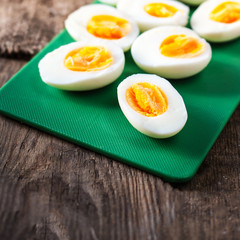 Hard boiled eggs, sliced in halves on cutting board wooden backg