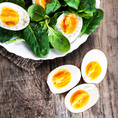 Fresh  green spinach baby leaves and boiled eggs cut in a half o