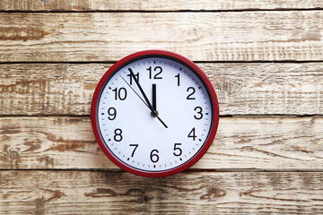 Red round clock on a grey wooden table